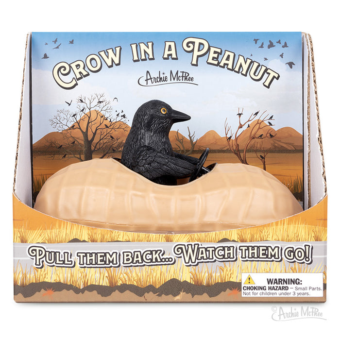 The "Crow in a Peanut" is a soft vinyl creation featuring a toy crow inside a peanut-shaped vehicle, elegantly perched on a display stand with the text "Crow in a Peanut." This playful and charming piece also functions as a pull-back corvid car and includes an important safety warning label.