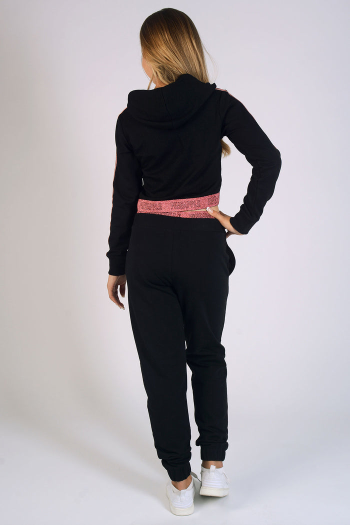 Girl wearing black Jacquard Tape Joggers and matching long sleeve crop hoodie with rose gold logo detailing