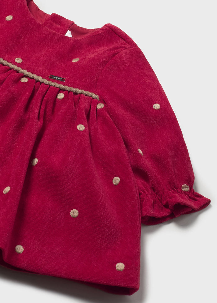 Closeup of Mayoral baby girl dress showing Cherry Red polka dot fabric, trim detail, and lining.