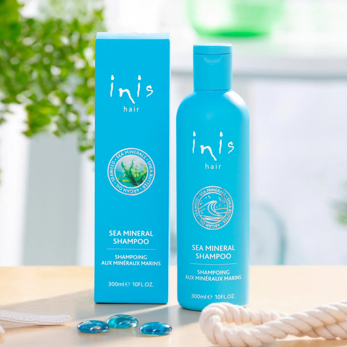 Blue 'inis hair' sea mineral shampoo bottle and packaging on a wooden surface with blurred greenery in the background.