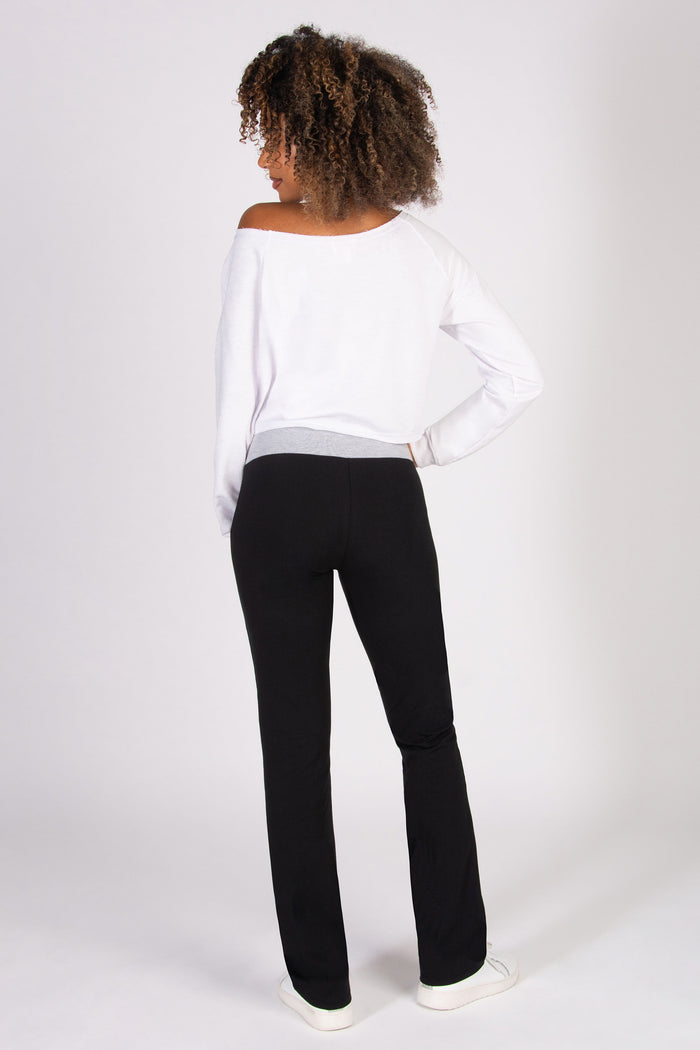 Person wearing a white top and black flared trousers on a white background