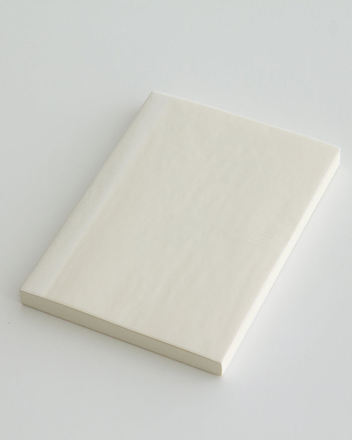 Angled silhouetted midori square grid thick a5 notebook against white background.