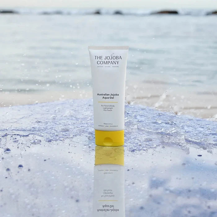 Tube of aqua gel sitting on a mirrored surface with a blurred ocean background.