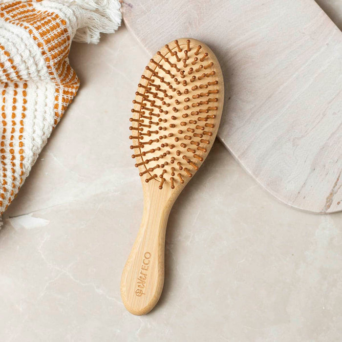 Bamboo hair brush styled on a counter with a towel.