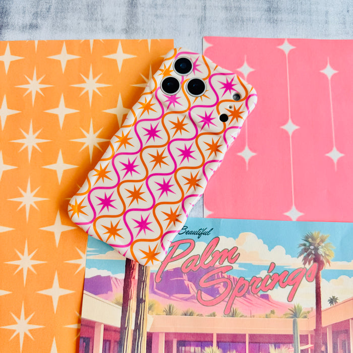 Trendy wavy iPhone case featuring a pink and orange starburst geometric pattern on a cream background with a high-gloss finish.