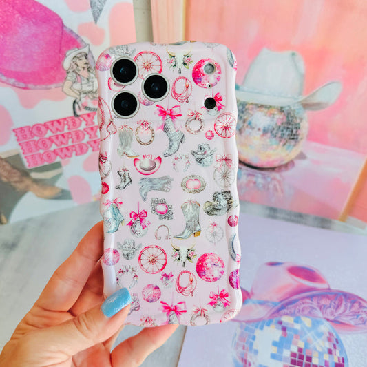 Hand holding the Disco Cowgirl Wavy Luxe MagSafe iPhone case, showing the pink western print with cowboy boots, hats and disco ball motifs.