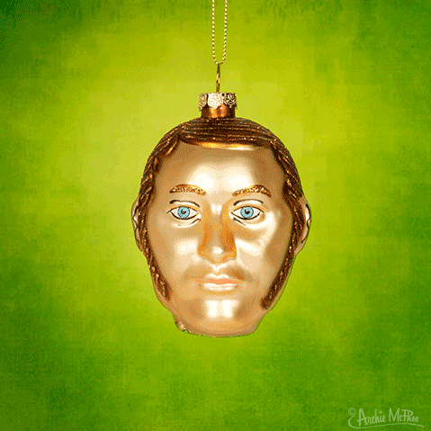 A Dr. Jekyll & Mr. Hyde Ornament featuring a head with blue eyes stands out against a green background, symbolizing the dual nature of its namesake characters.