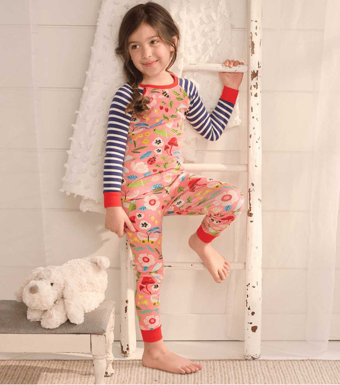 Girl wearing Hatley Enchanted Garden pajamas with striped raglan sleeves and colorful floral print.