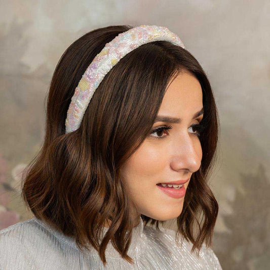 A woman wearing a floral puff hair band in pastel colors.