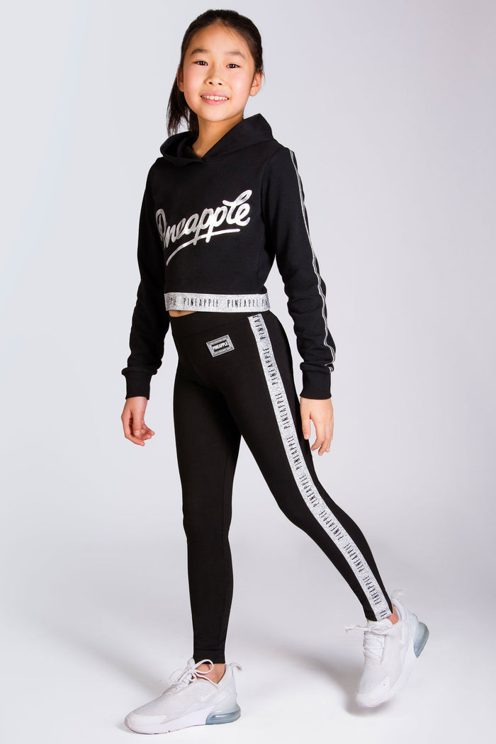 Girls' black dance leggings with silver glitter tape along the legs and a Pineapple logo on the hip.