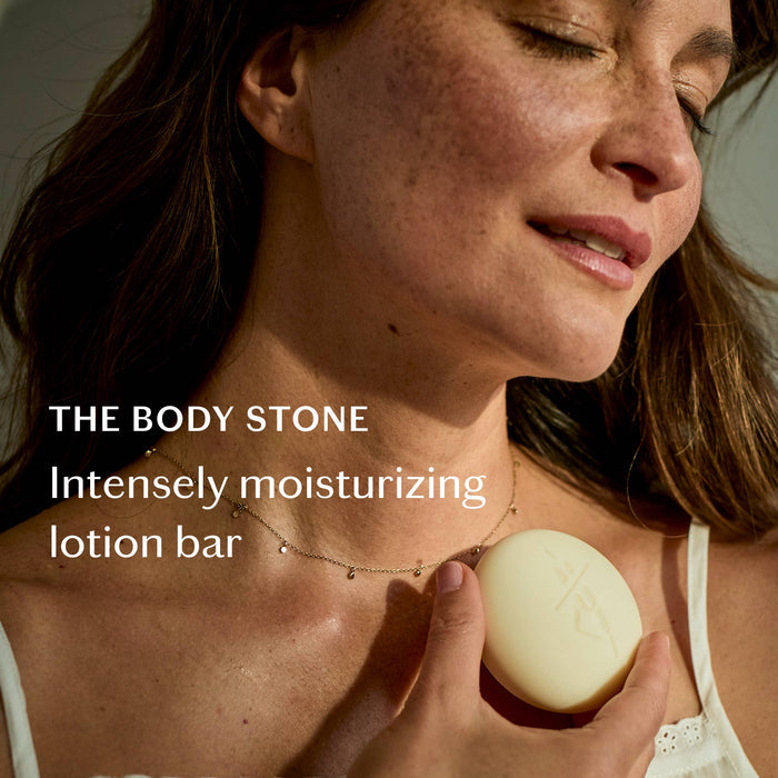 Woman holding a lotion bar with text 'THE BODY STONE Intensely moisturizing lotion bar' on a neutral background