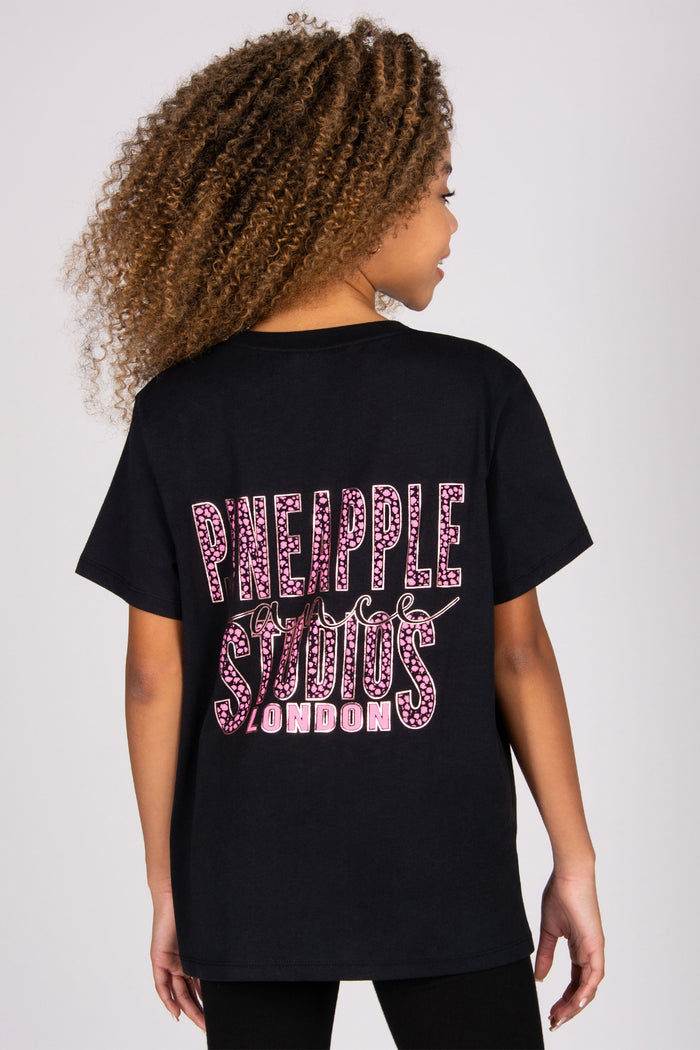 Person wearing a black t-shirt with 'Pineapple Studios London' text on the back against a white background