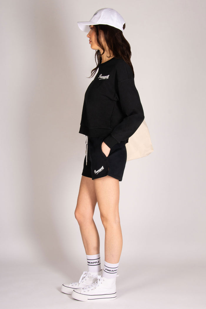 Women's black sweatshirt paired with pocket shorts, trainers and cap to complete the ultimate athleisure look.