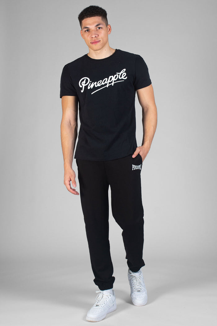 Man wearing black T-Shirt with white logo and black track pants