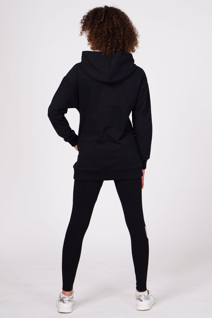 Girl wearing Black Longline Logo Hoodie and black full-length leggings