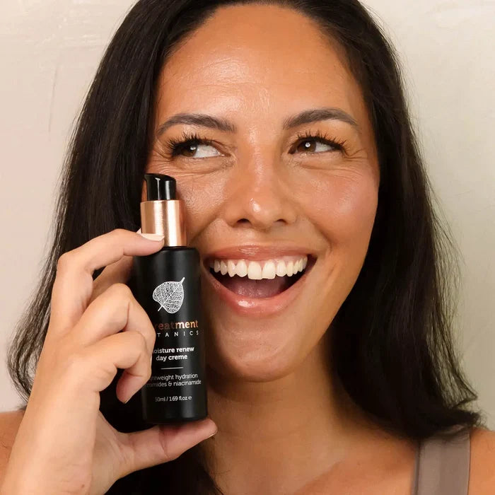 Woman holding renew day creme bottle up to her cheek with a happy expression.