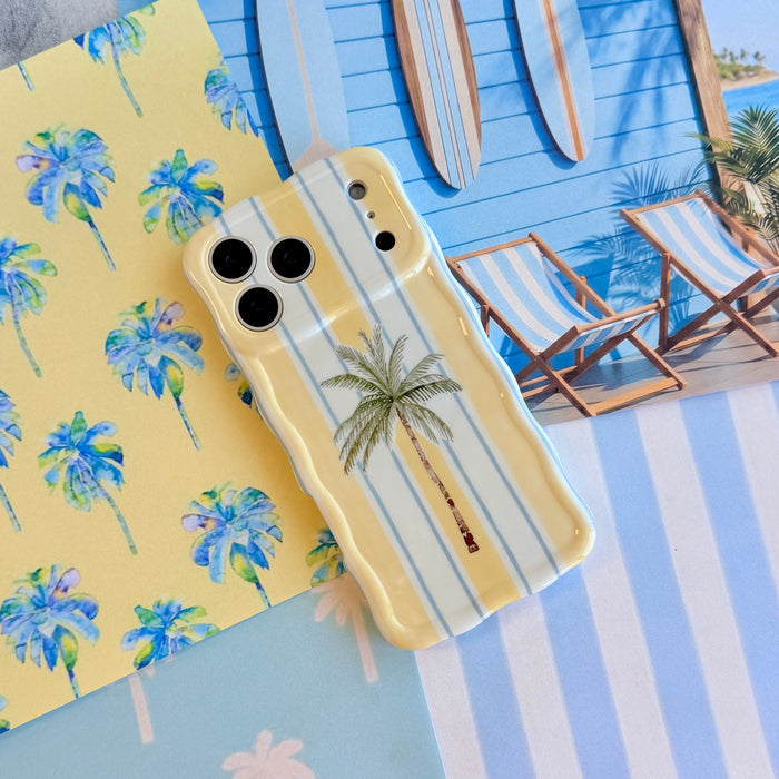 Palm Shore Club Wavy Luxe MagSafe iPhone case styled against a beach club backdrop with striped deck chairs and surfboards.