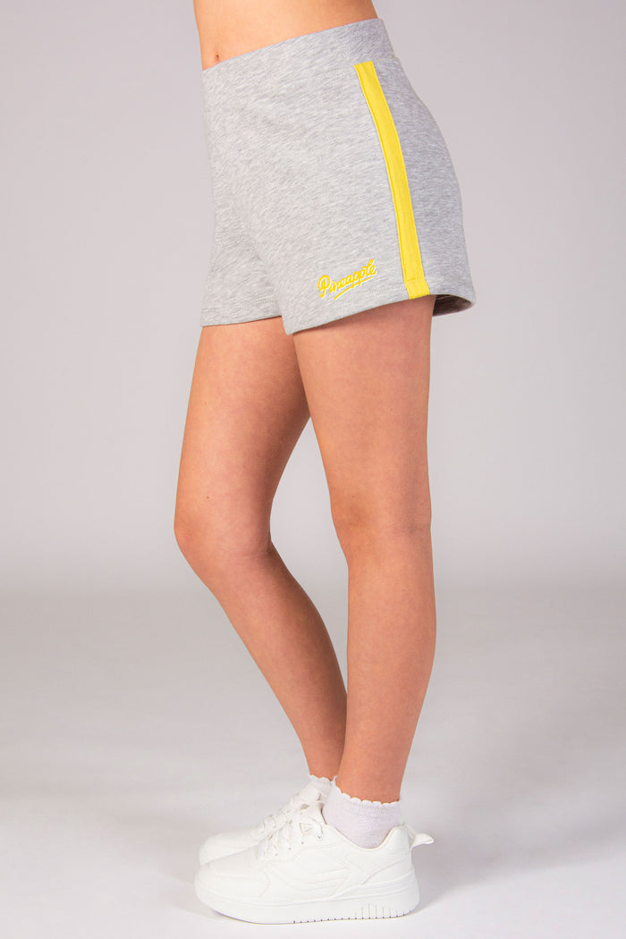Girls' grey sports shorts with yellow stripe and small Pineapple Dance Studios logo