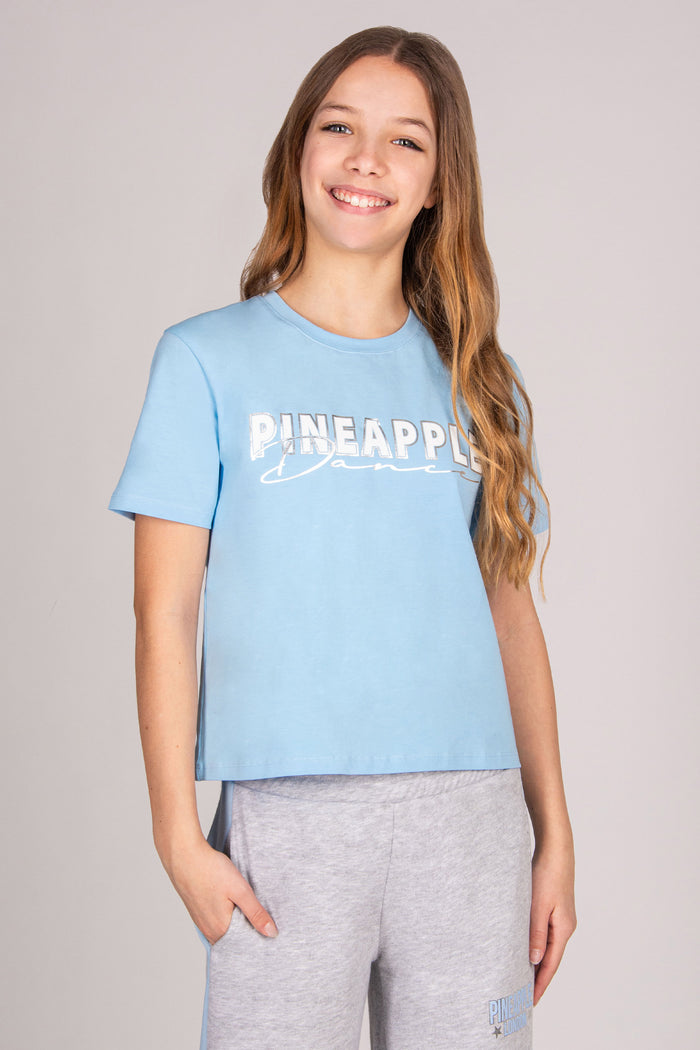 Girl wearing a regular fit blue t-shirt against a plain background.