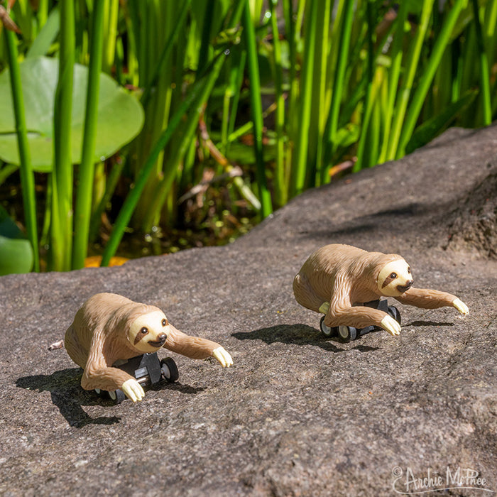 The Racing Sloths, made from soft vinyl, sit atop a rock surrounded by vibrant greenery. Equipped with wheels for swift movement, these energetic creatures add an adventurous flair to their natural habitat.