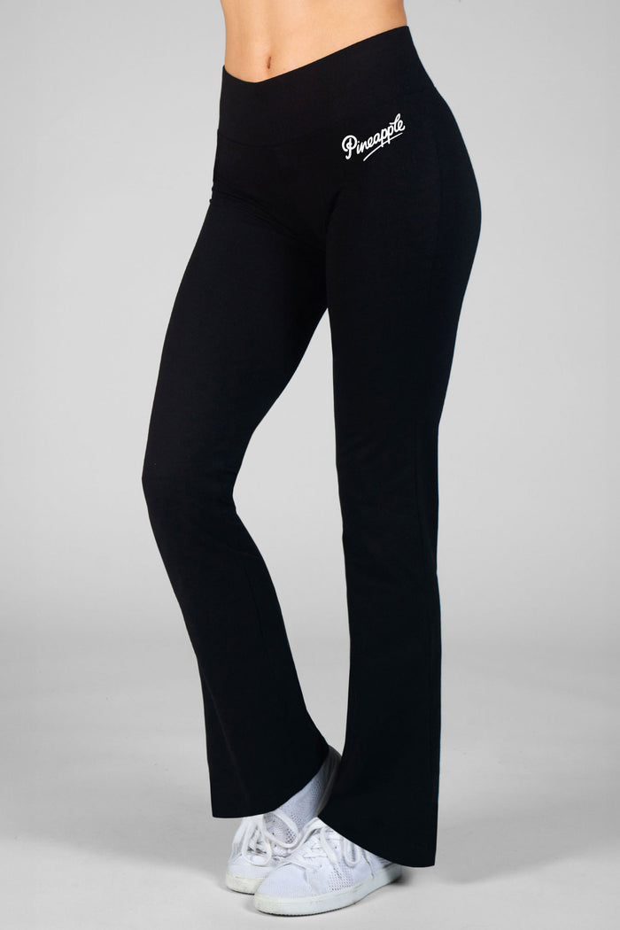 Woman wearing black bootcut yoga pants on a plain background.