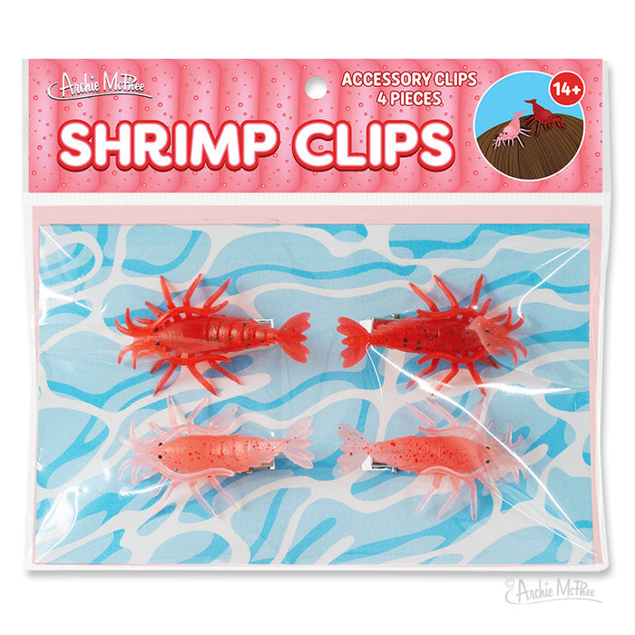 Shrimp Clips are a set of four soft vinyl hair clips shaped like shrimp, perfect as fun crustacean accessories for your collection, shown on a blue and white background.