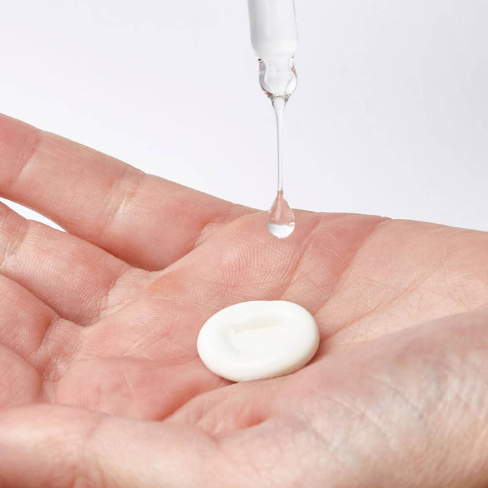 Dollop of white cream on a person's hand.