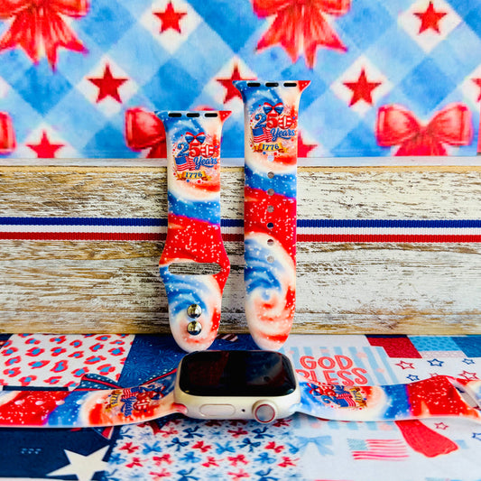 Sweet Freedom 250 silicone Apple Watch band celebrating America's 250th anniversary with "250 Years 1776" emblem, American flag, fireworks, red bow, and red, white, and blue tie-dye swirl with star sparkle, shown displayed and worn on Apple Watch against a patriotic 4th of July backdrop.