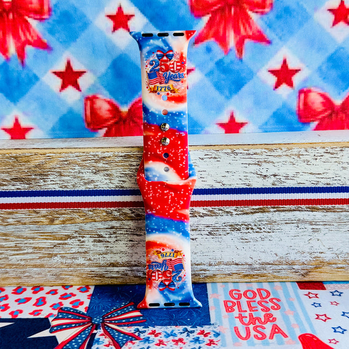 Sweet Freedom 250 silicone Apple Watch band celebrating America's 250th anniversary with "250 Years 1776" emblem, American flag, fireworks, red bow, and red, white, and blue tie-dye swirl with star sparkle, shown displayed and worn on Apple Watch against a patriotic 4th of July backdrop.