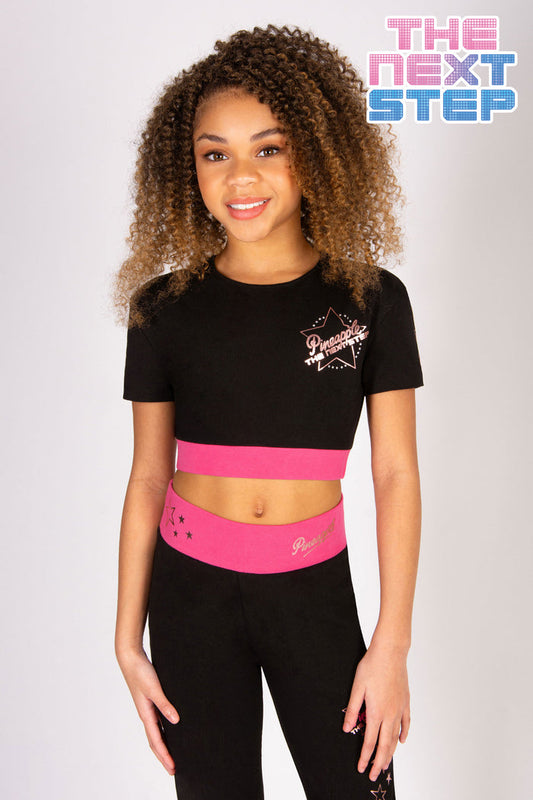 Black short sleeve crop top with contrasting pink elasticated waistband featuring a small The Next step Dance logo.