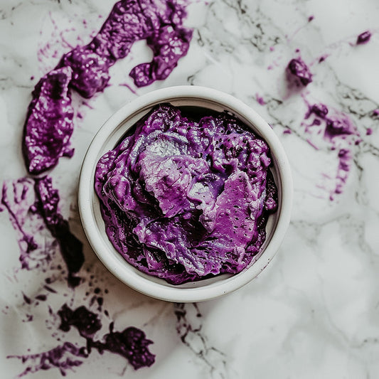 A small open container of ube jam spilled over the sides on a marble surface.