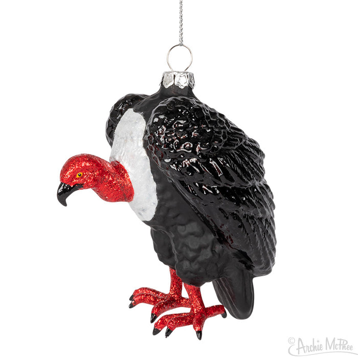 The Vulture Ornament, featuring a red head and black body crafted from hand-blown glass, elegantly hangs from a silver string, offering a unique addition to your Christmas decorations.