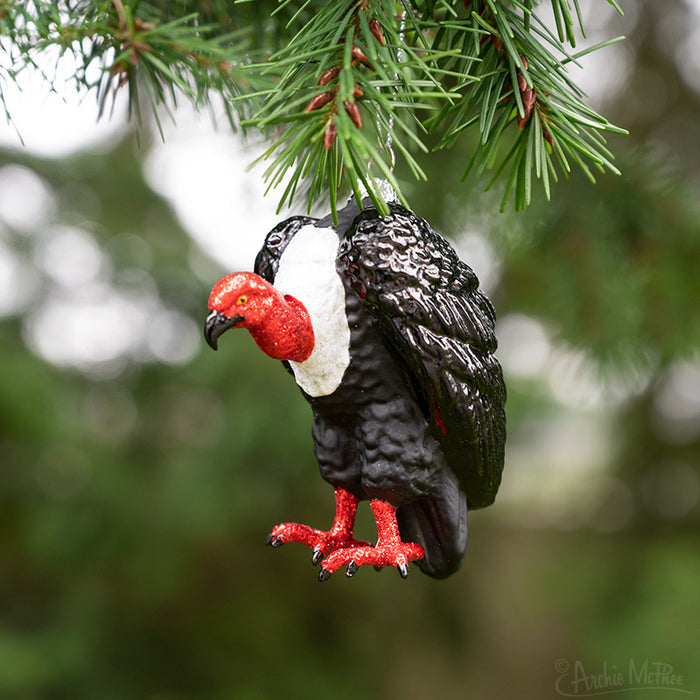 The Vulture Ornament, crafted from hand-blown glass, perches elegantly on the tree branch, adding a unique touch of intrigue to the scene.