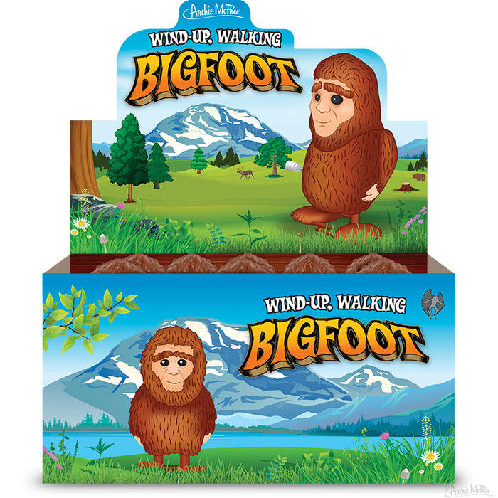 An illustration of a cartoon Bigfoot figure standing in a forest with mountains, accompanied by an illustrated display box showcasing the Wind-Up Bigfoot.